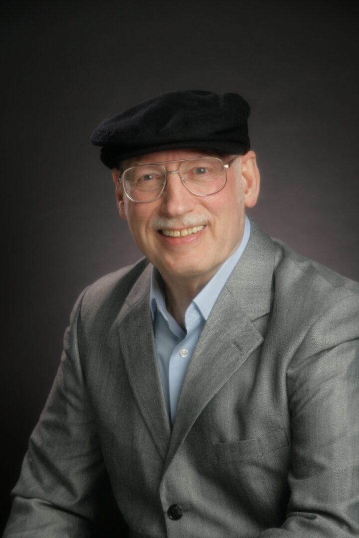 A smiling man in a black hat and a gray suit